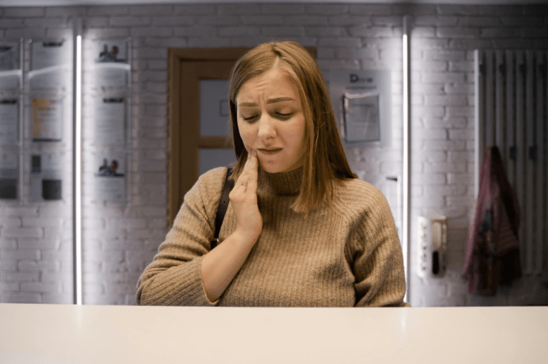 Woman touching her cheek, showing discomfort or pain.
